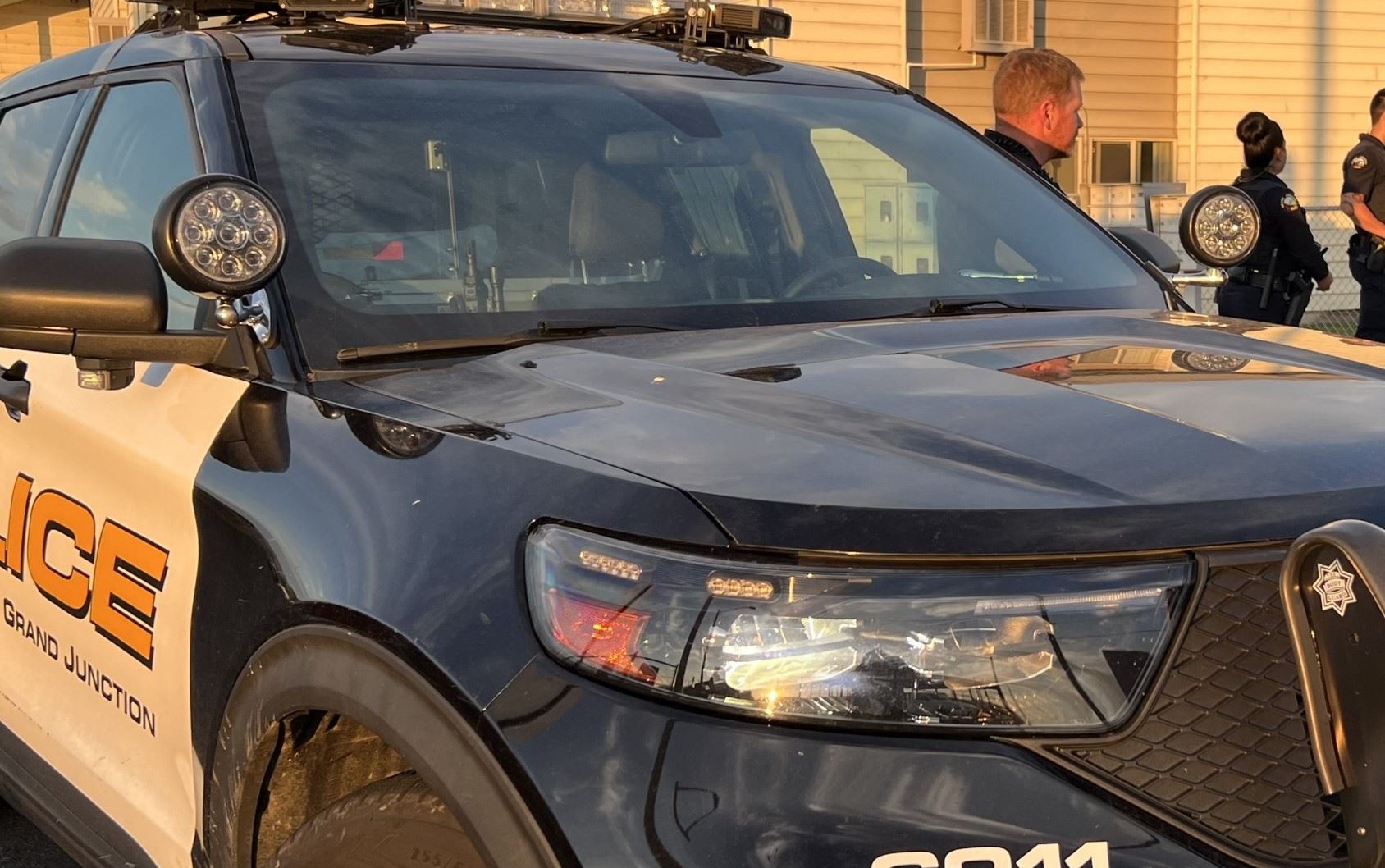 Grand Junction Police vehicle with three officers standing next to it at an incident