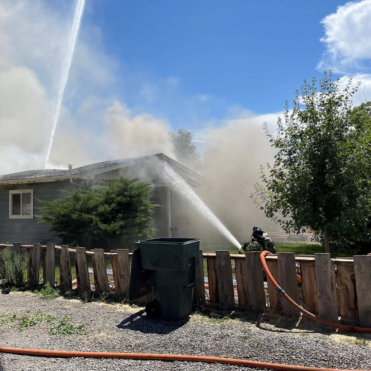 Two Grand Junction Fire Department firefighters spray water on a house fire