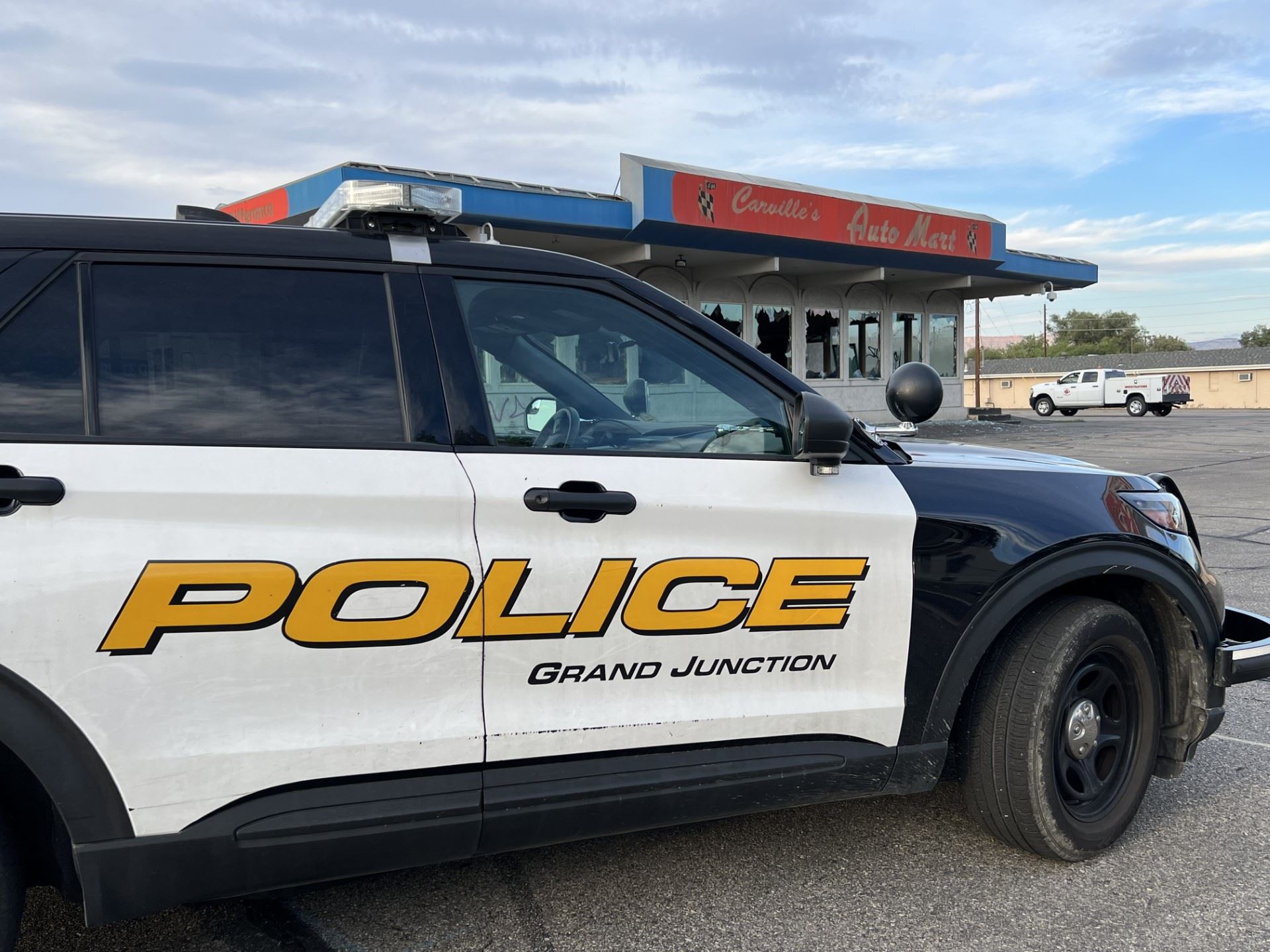 Police car in front of auto dealership business with white fire investigations truck in background