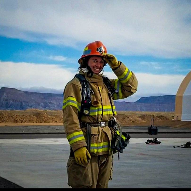 Firefighter and Paramedic in full firefighter attire holding a helmet