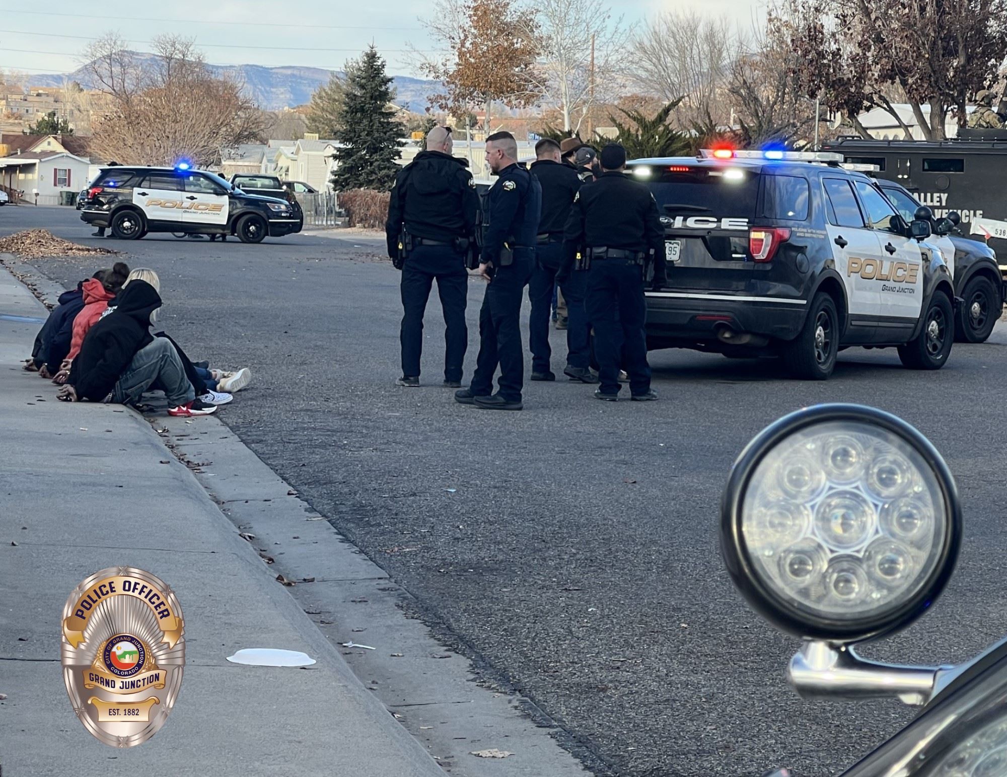 Grand Junction Police Officers with arrestees on sidewalk at incident with cop cars in background