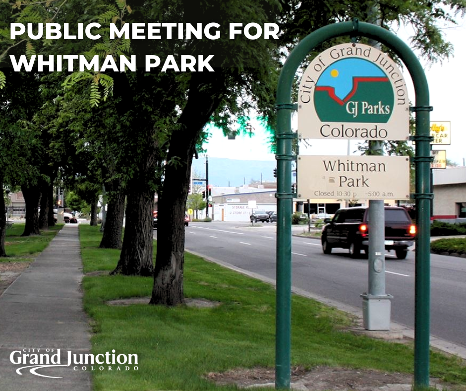 A sign at Whitman Park with information about the park and rules. Trees in the background. 