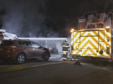 Fire Crew trying to put out fire next to Fire Truck while mobile home is smoking