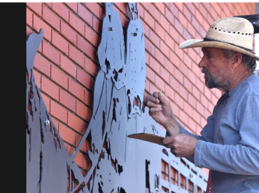 man painting black paint on station 6 art