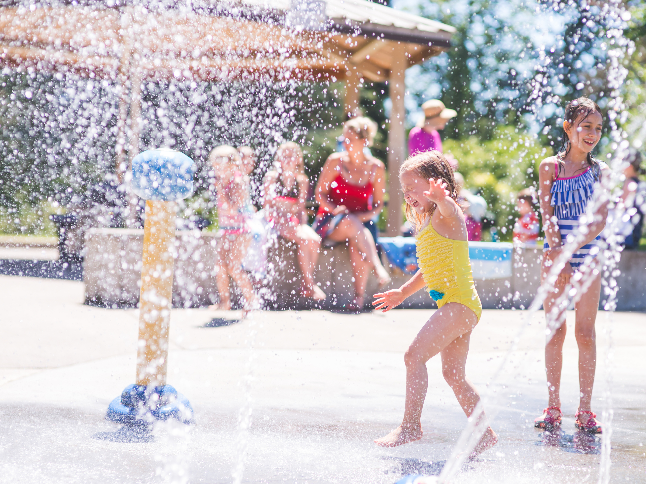 girl running through water sprays