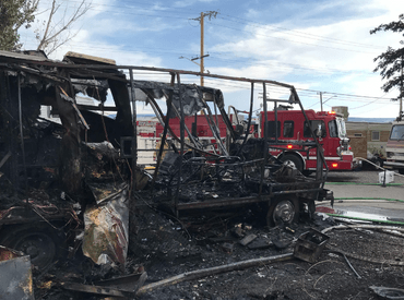 Burned motor home with fire engine in background