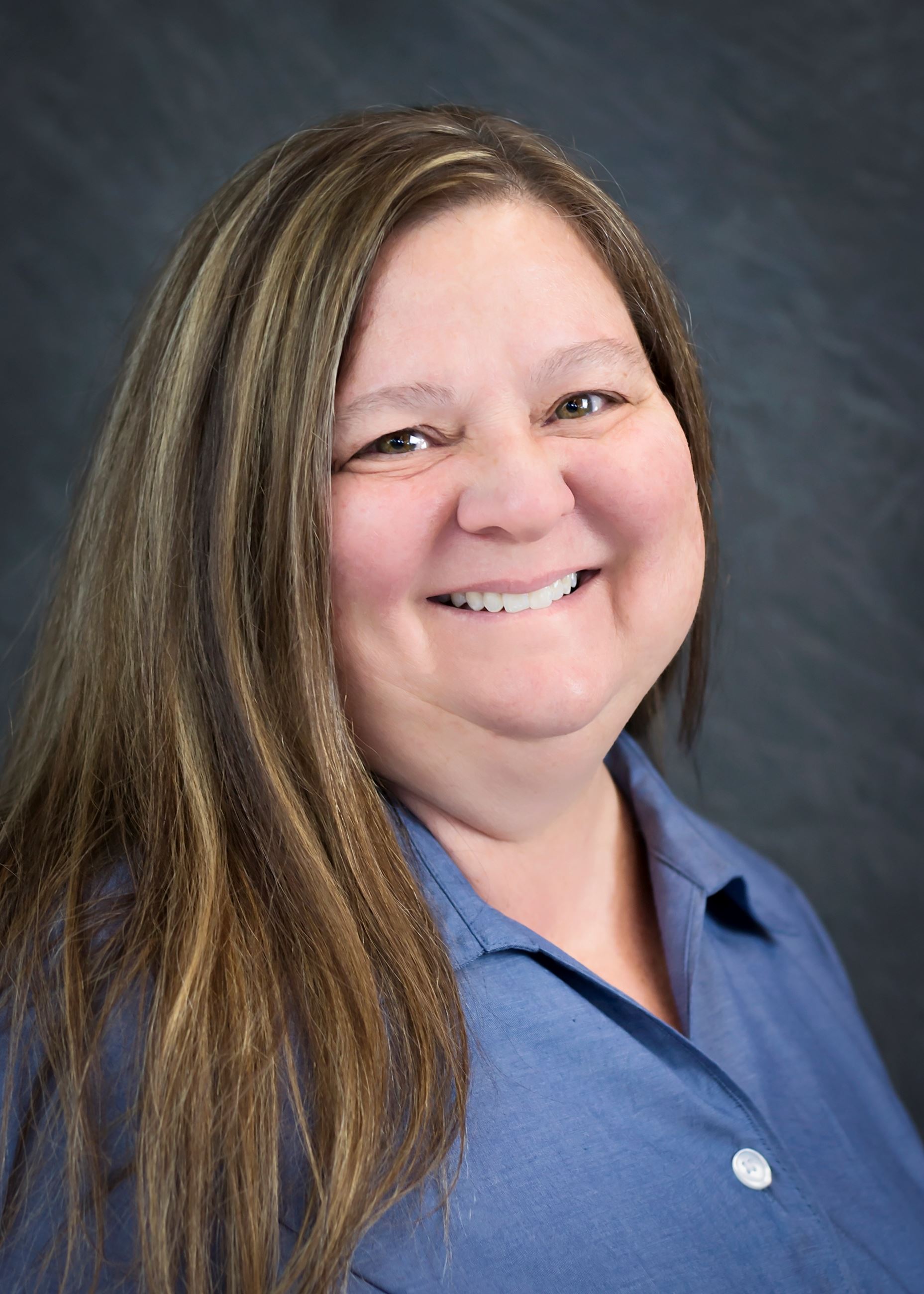 Caucasian woman with long brown hair in blue shirt