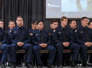 Recruits sitting on the stage waiting to be pinned by their loved ones during graduating ceremony