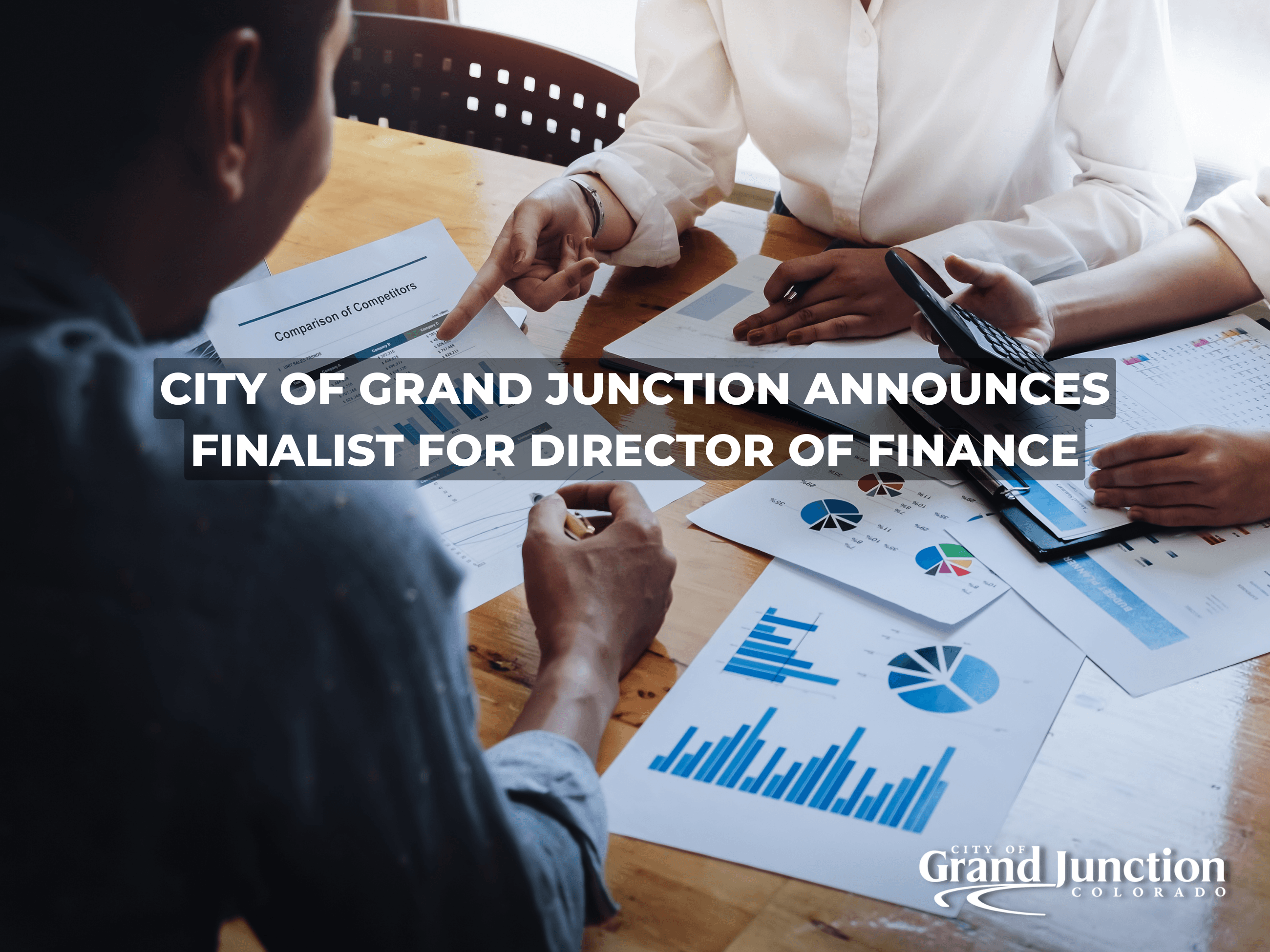 Desk space with papers and three people's hands. Text included. Indoors. 