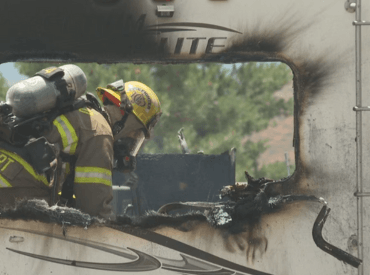 Firefighter in uniform seen outside burned RV window
